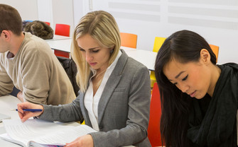 [Translate to English:] Studierende arbeiten und blicken auf ein Aufgabennblatt.