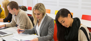 [Translate to English:] Studierende arbeiten und blicken auf ein Aufgabenblatt.