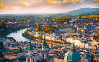 Luftaufnahme von Wien mit Fluss, mehreren Brücken und historischen Gebäuden mit Kuppeln im Vordergrund