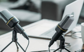 [Translate to English:] A table with microphones, a laptop and a cup