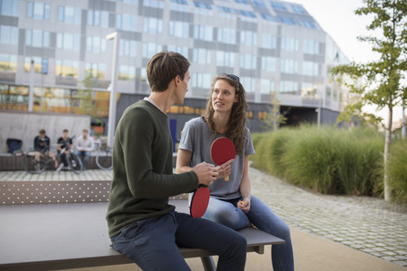 Zwei Studierende sitzen auf einem Tischtennistisch und reden