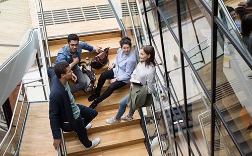 Vier Studierende sitzen auf einer Stiege