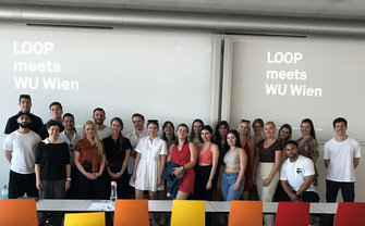 our students and Monika Koller standing in front of a screen saying LOOP meets WU Wien