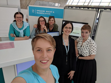 Department staff standing in front of a poster reading "Sprache, Macht and Manipulation"