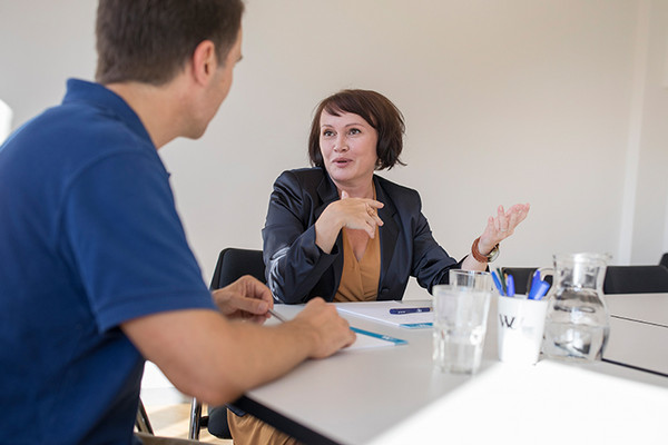 Ein Mitarbeiter und eine Mitarbeiterin sitzen an einem Besprechungstisch und unterhalten sich