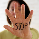 Foto einer Frau, die eine Hand vor die Kamera streckt, auf der in schwarzem Buchstaben "STOP" steht