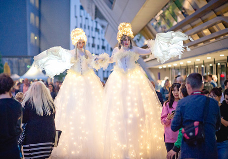 Stelzengeherinnen mit weißen Gewändern und vielen Lichtern beim Sommerfest auf dem Campus WU.