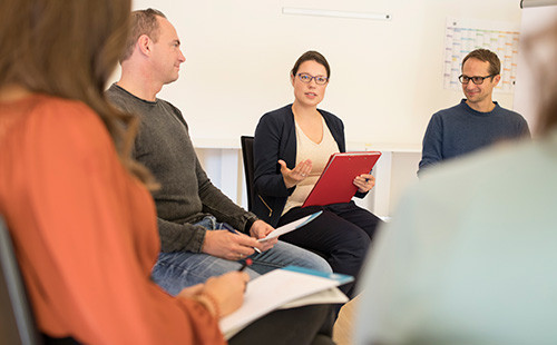 Eine Gruppe von Menschen sitzt im Kreis und redet miteinander