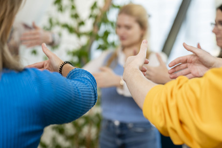 Studierende stehend im Kreis, Hände vor dem Körper haltend