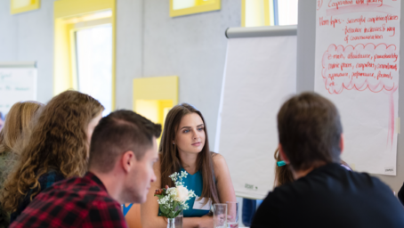 Group of students discussing text on a flip chart.