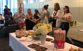 students talking in the department's lounge, in the front a table with food