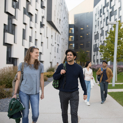 Studenten und Studentinnen mit Rucksäcken gehen aus dem D4 Gebäude am WU Campus