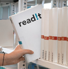 Abgebildet ist eine Hand, die ein weißes Buch aus einer Reihe von Büchern aus einem Bibliotheksregal zieht. Das Buchcover trägt den Schriftzug "readit".