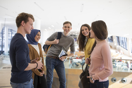 Five students standing in a half-circle and chatting