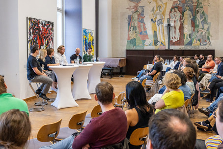 Eine Podiumsdiskussion beim Auftakt des Hackathons mit breitem Publikum.