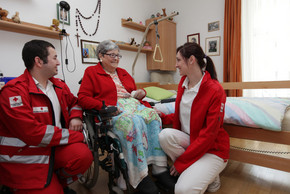 Employees of the Austrian Red Cross taking care of an old woman