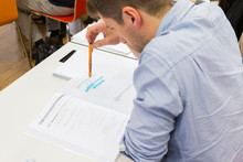 Ein Student schaut konzentriert in seine Unterlagen während er einen Stift hält