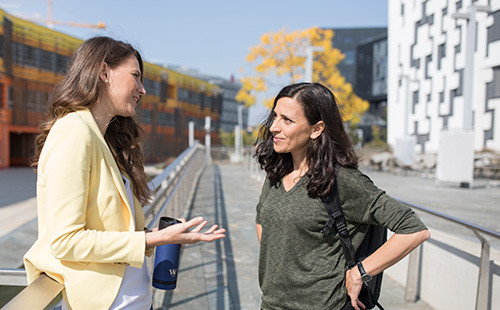 Zwei Studierende stehen vor dem D4 und reden miteinander