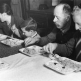 Schwarz-weiß-Foto zeigt Umsiedler*innen in Innsbruck bei der ersten Mahlzeit auf deutschem Gebiet.