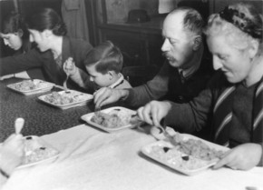 Schwarz-weiß-Foto zeigt Umsiedler*innen in Innsbruck bei der ersten Mahlzeit auf deutschem Gebiet.
