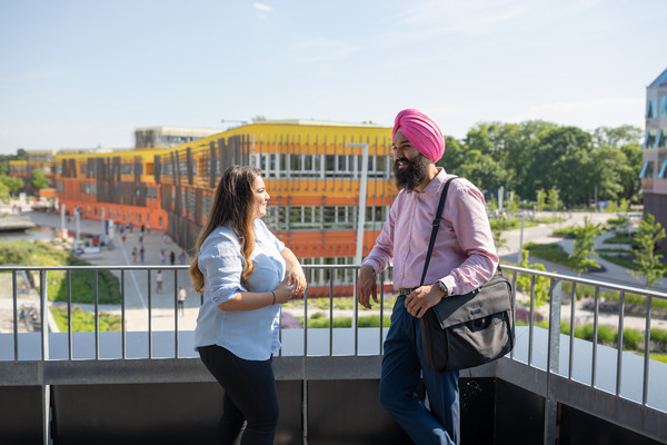 Austausch-Studenten stehen auf der Terrasse des EA Gebäudes und unterhalten sich