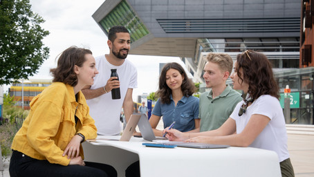 A group of students sitting outside. They are discussing how to participate at an international case competition.