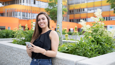 Here you see a student standing in front of a flower. She is looking for tips on how to act envirnomental-friendly while abroad.