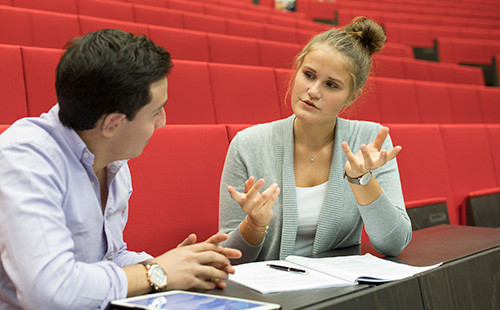 Zwei Studierende tauschen sich im Hörsaal aus