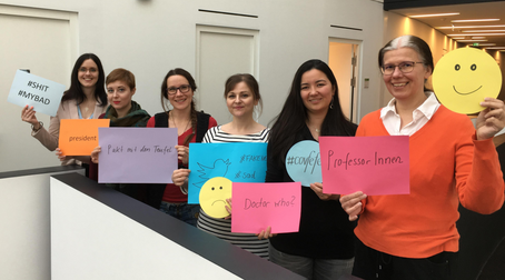 Six members of staff holding up cards related to their areas of research