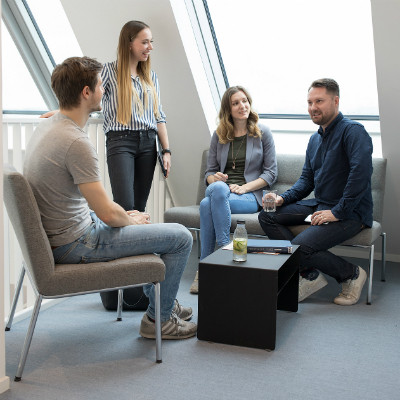 Three students discussing a topic with a teacher in a corner area