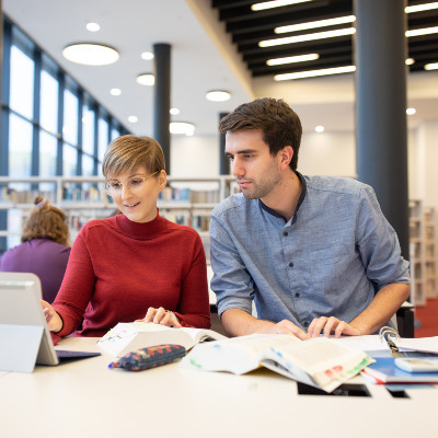 Ein Student und eine Studentin lernen auf einem Tisch in der D4 Bibliothek