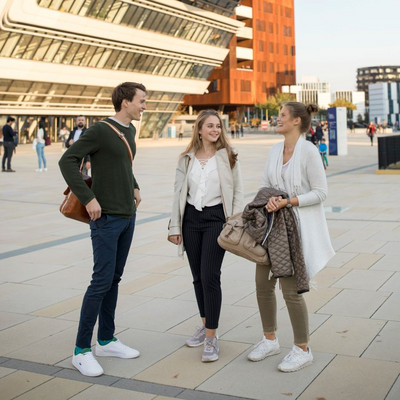 3 students stand in front of the library building and talk to each other