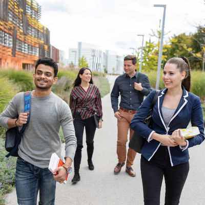 4 Studenten und Studentinnen gehen vor dem Department für Wirtschaftsrecht spazieren 