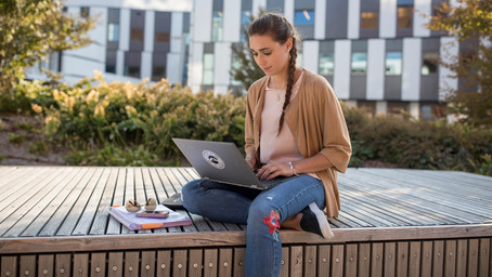 A students sits in front of her laptop and participates in an online group meeting.