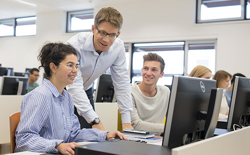 Ein Vortragender erklärt Studierenden etwas am PC