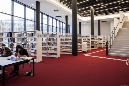 Lerntische und dahinterstehende Bücherregale in der Bibliothek