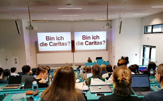 a picture taken during Caritas' presentation showing students, the lecturer and one of the slides