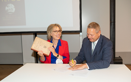 Dr. Karina Urbach receives the book that once belonged to her great-grandfather from Nikolaus Berger 