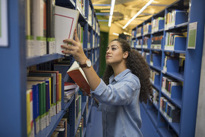 Stundentin sucht ein Buch in der Bibliothek.