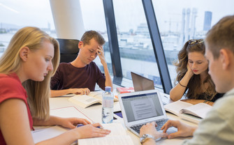 Gruppe von Studierenden sitzt überanstrengt am Tisch.