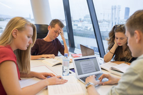 Gruppe von Studierenden sitzt überanstrengt am Tisch.