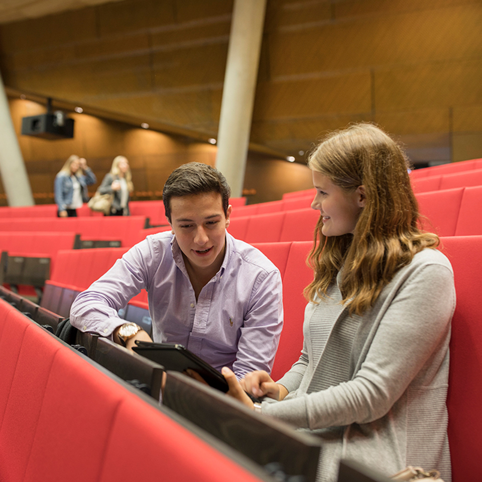 Ein Stundent und eine Studentin sitzen im Audimax und unterhalten sich